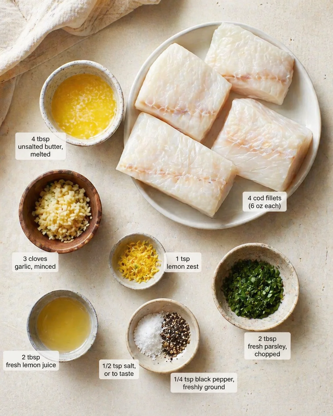 Measured ingredients arranged for Baked Cod Recipe (Easy, Flaky & Flavorful): 4 cod fillets (6 oz each, about 1-inch thick), fresh or thawed from frozen, 4 tbsp unsalted butter, melted, 3 cloves garlic, minced, 1 tsp lem