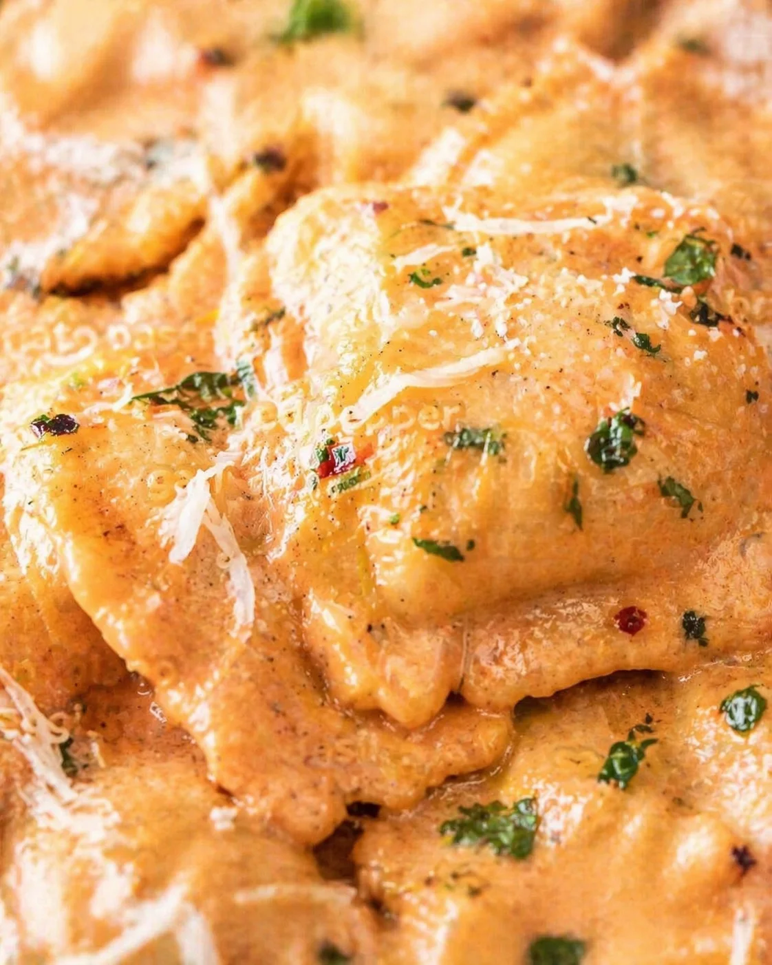 Close-up of crispy, parmesan-topped chicken pieces sprinkled with chopped parsley.