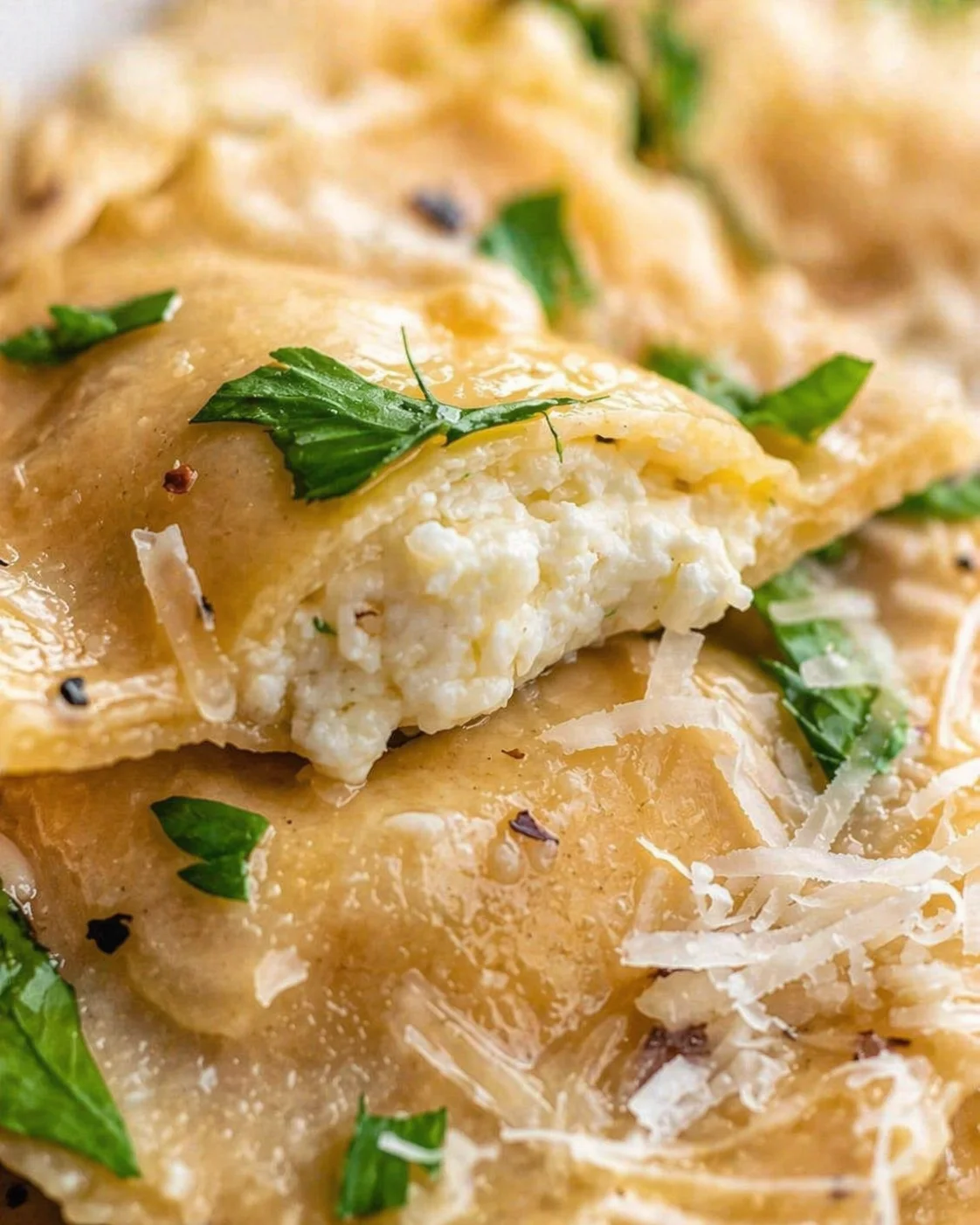 Close-up of golden flaky phyllo pastries filled with creamy cheese, garnished with parsley.
