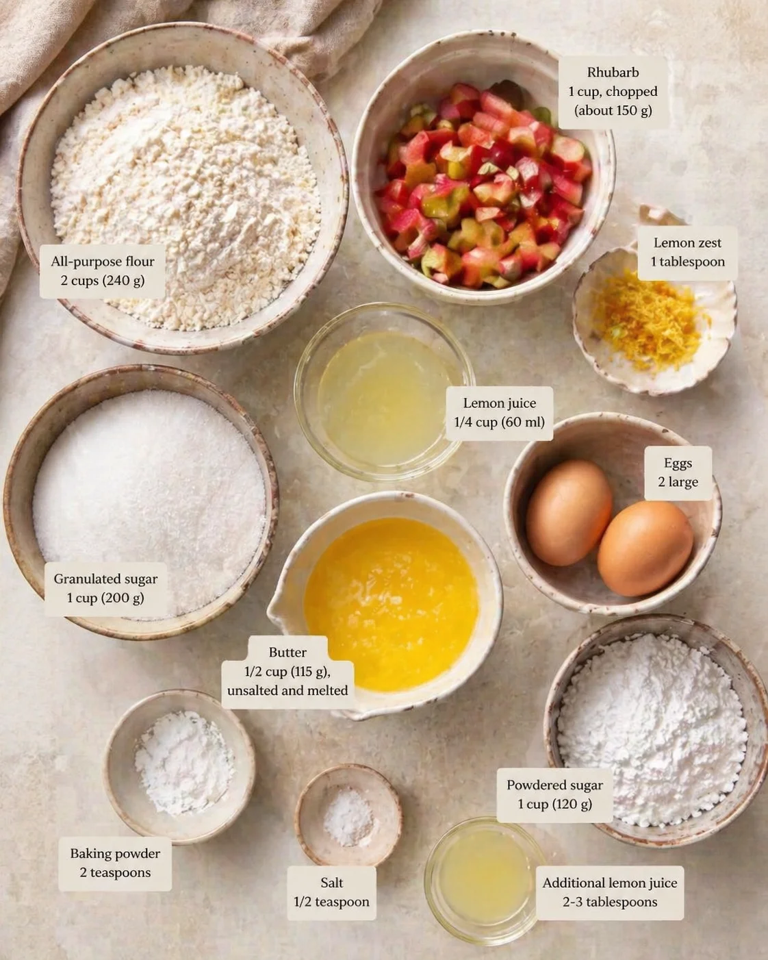 Overhead shot of baking ingredients in ceramic bowls with labeled measurements, including rhubarb, flour, sugar, eggs, butter, and lemon.