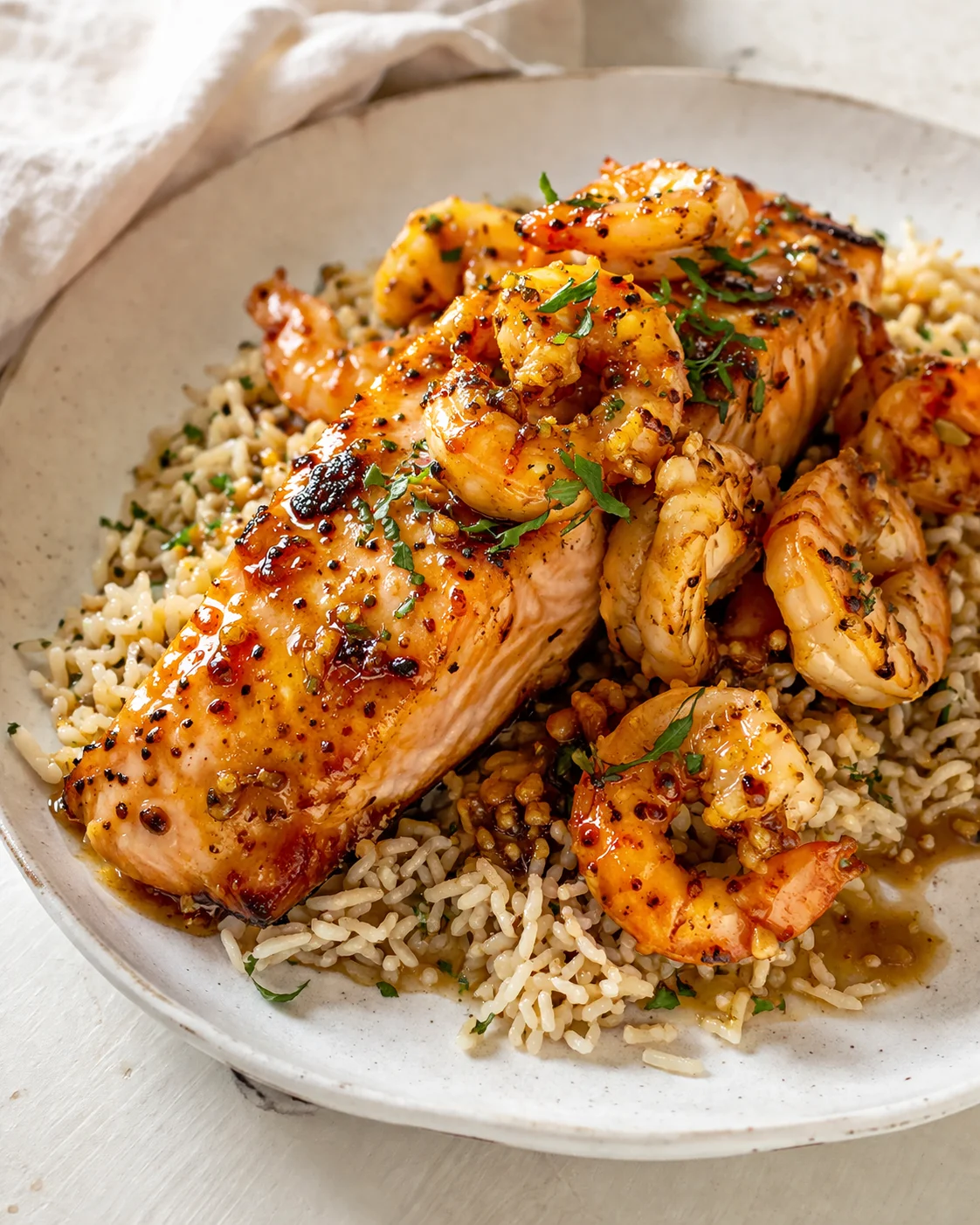 Golden salmon fillet with shrimp atop herb rice, garnished with parsley
