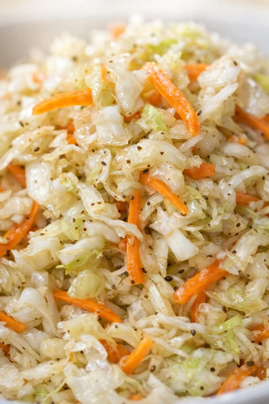 close-up of sautéed shredded cabbage and carrot with sesame seeds in a pan