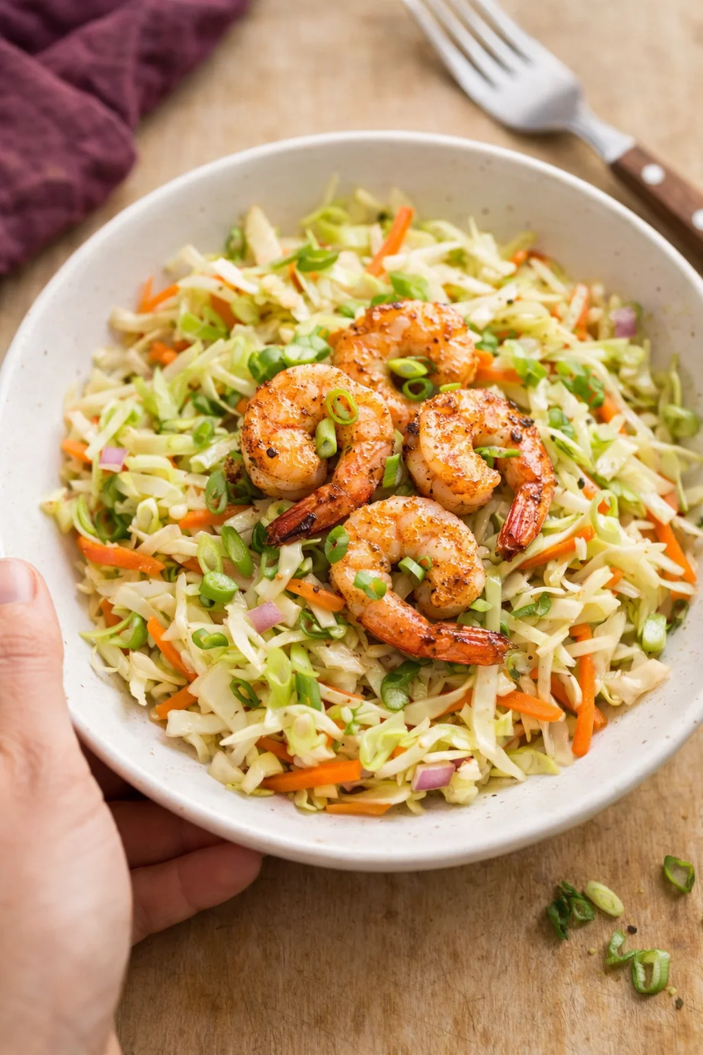 bowl of shrimp on colorful cabbage and carrot slaw with green onions