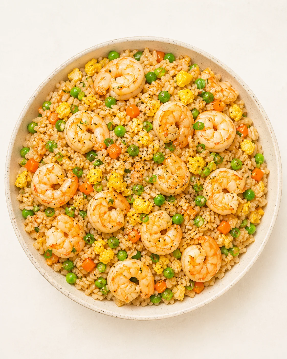 top-down view of a bowl of shrimp fried rice with peas, corn, and carrots