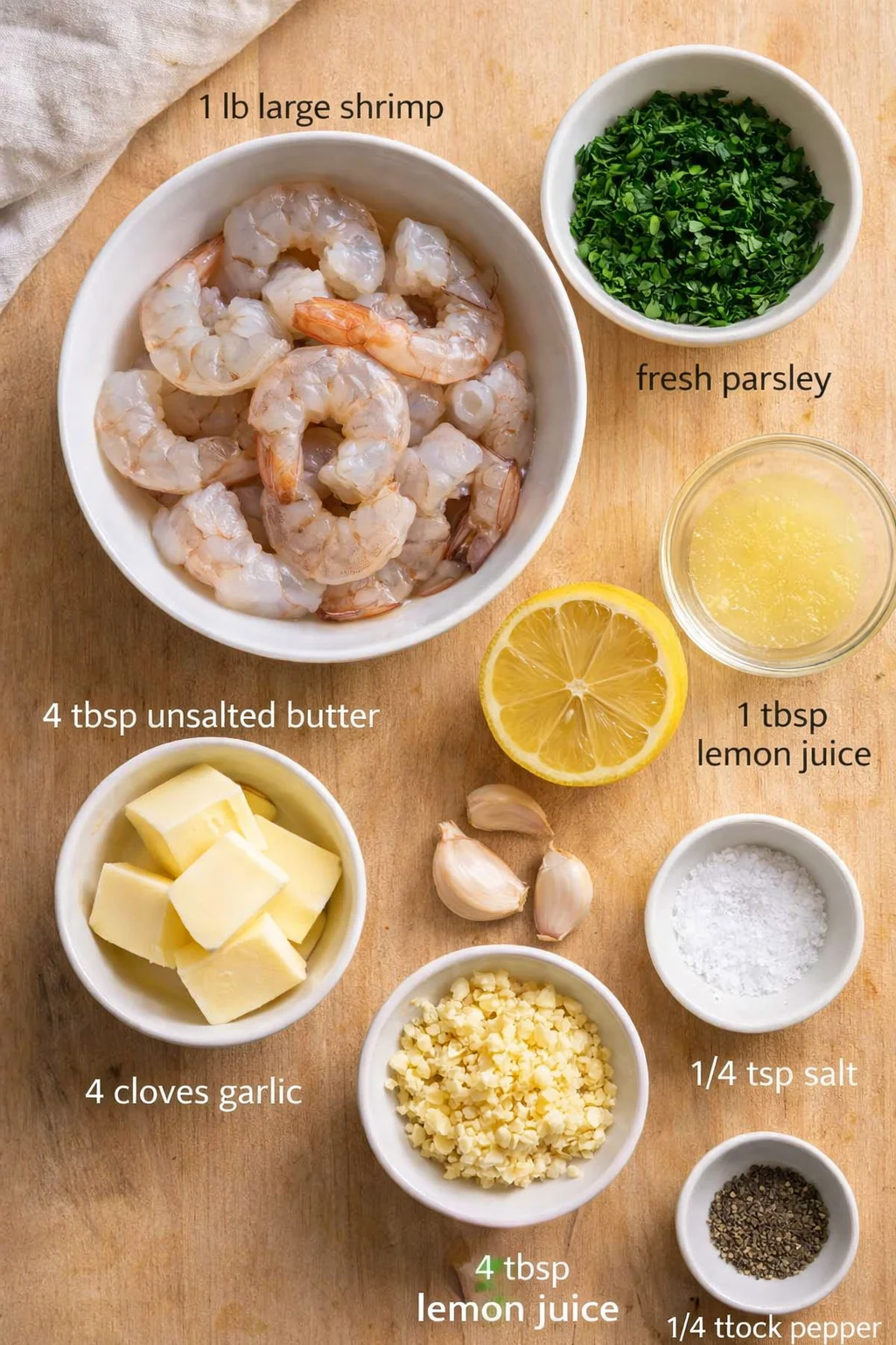 Top-down view of shrimp, butter, garlic, lemon, parsley and seasonings on a wooden board.