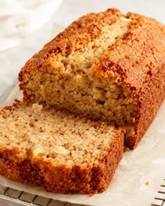 Moist banana bread loaf with golden crust, sliced to show tender crumb.