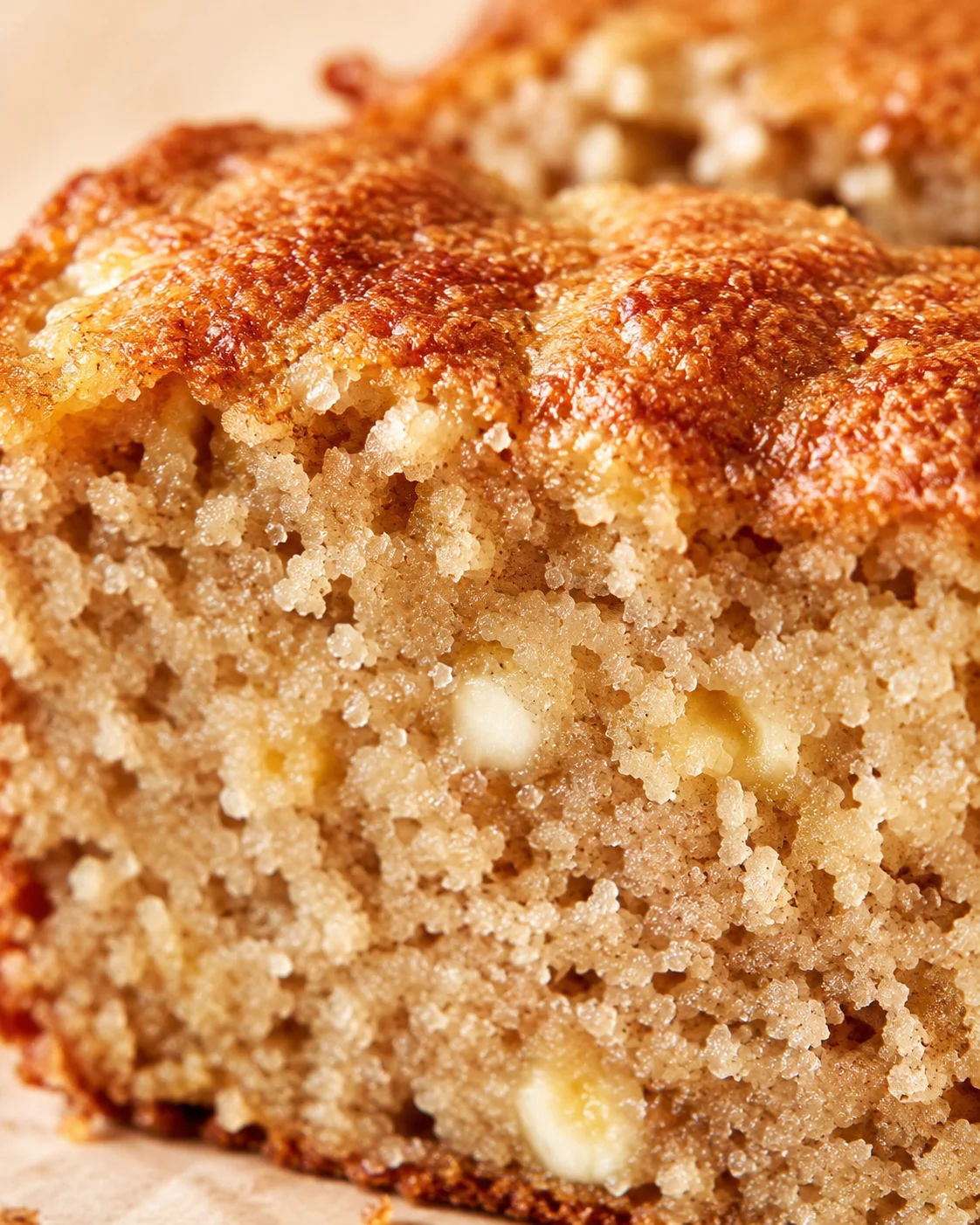 Close-up of a banana bread loaf with a caramelized crust and a moist, nut-filled crumb.