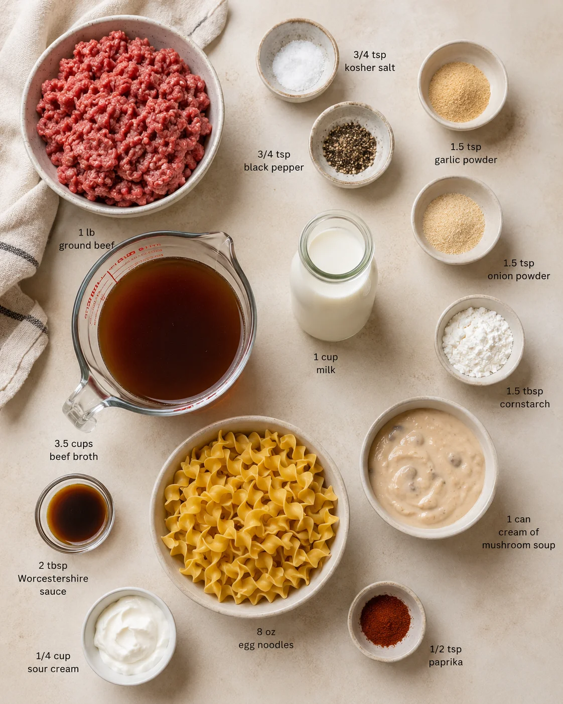 Overhead shot of an ingredients layout for beef noodle soup with labeled bowls and measurements