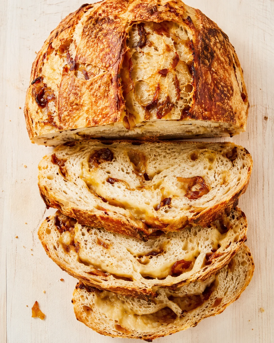 crusty round loaf filled with melted cheese and caramelized onions, sliced to reveal gooey interior