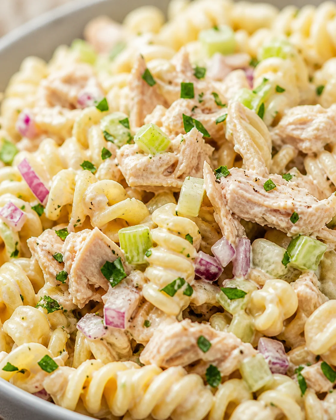 Creamy chicken pasta salad with rotini, celery, red onion, and parsley.