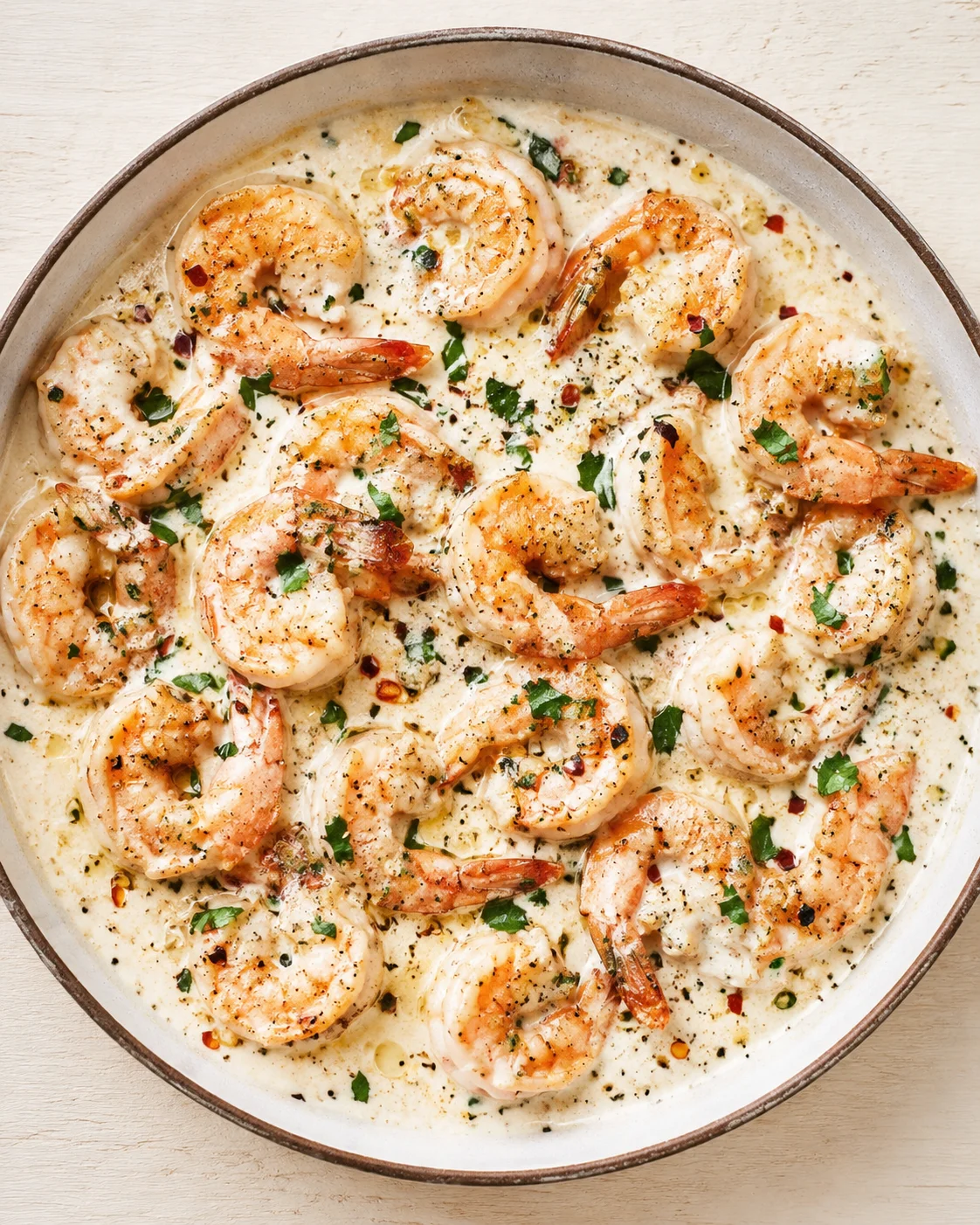 Shrimp in creamy garlic sauce with parsley in a round skillet
