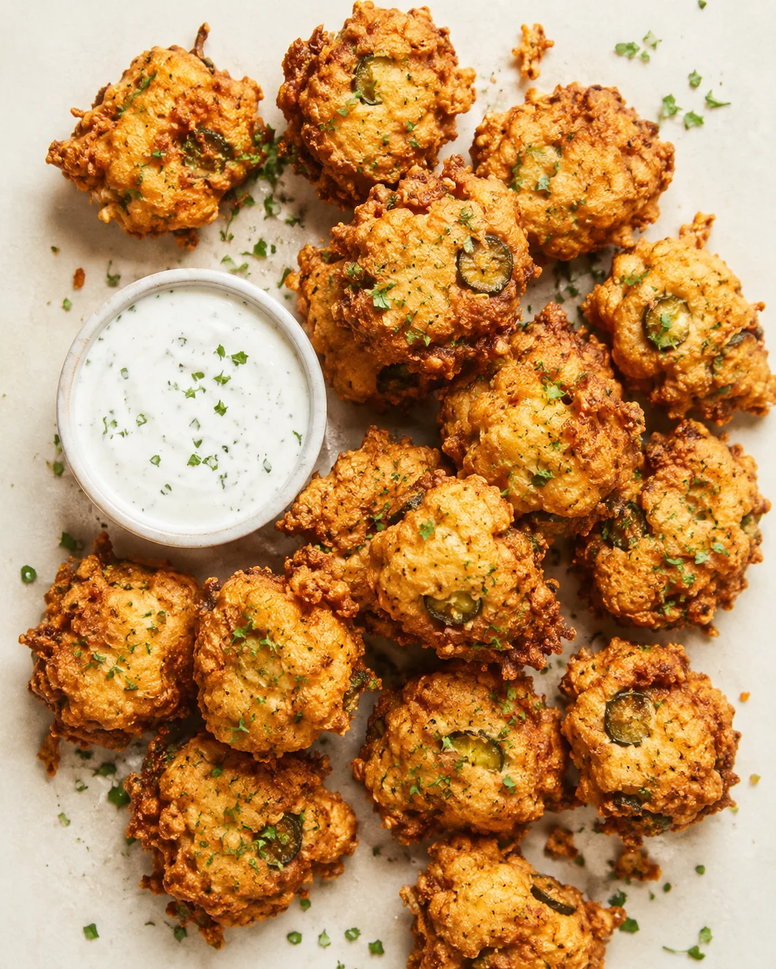 Golden-brown fried pickle bites with ranch dipping sauce on parchment