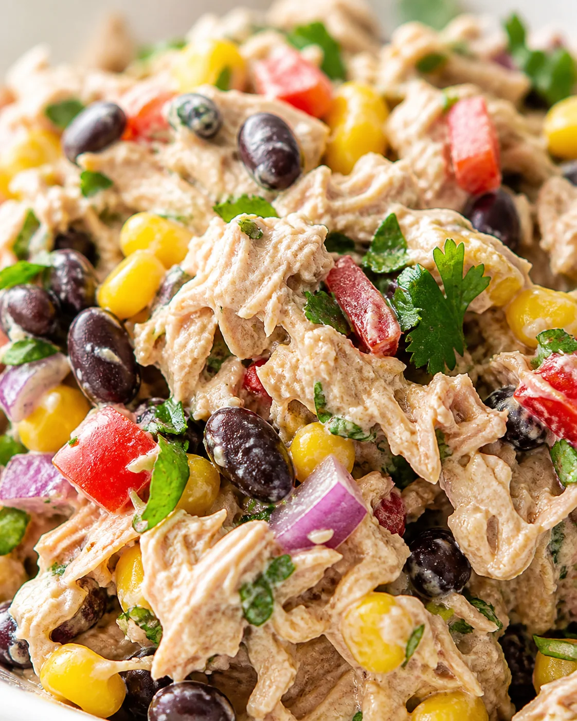 close-up of creamy southwest-style chicken salad with corn, black beans, red onion, peppers, and cilantro