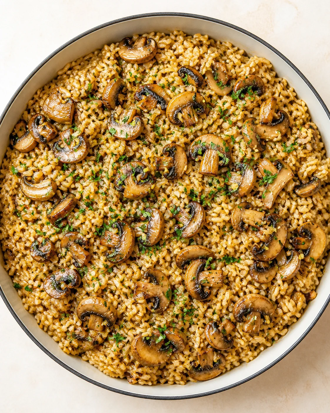 hearty brown-rice mushroom pilaf topped with sautéed mushrooms in a skillet