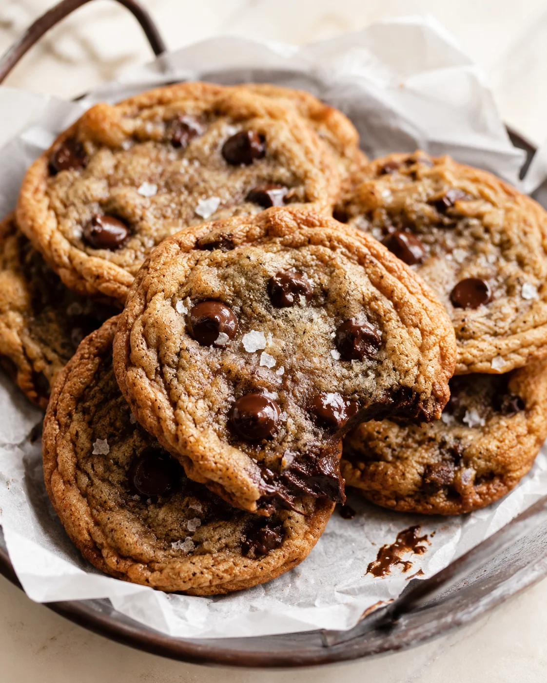 Close-up of warm chocolate-chip cookies with gooey centers on parchment-lined tray.