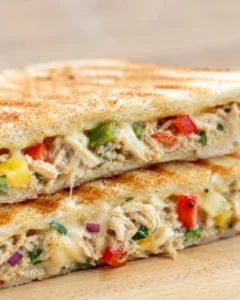 close-up of a toasted sandwich filled with creamy chicken, peppers, and melted cheese