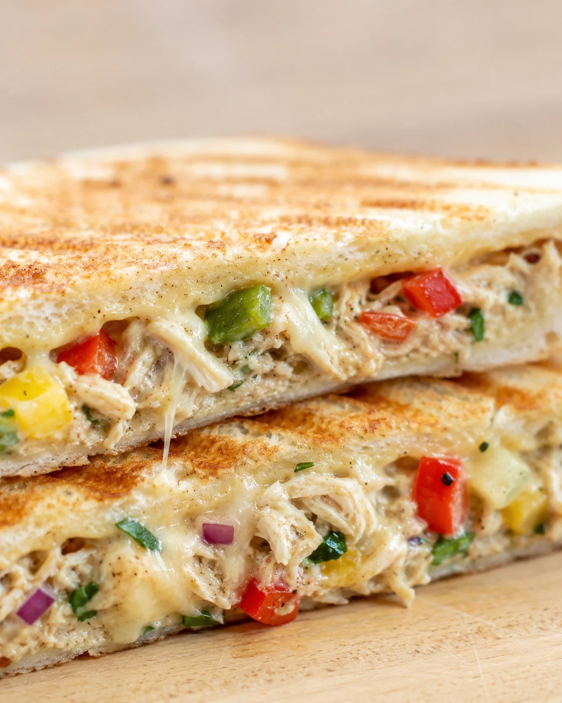 close-up of a toasted sandwich filled with creamy chicken, peppers, and melted cheese