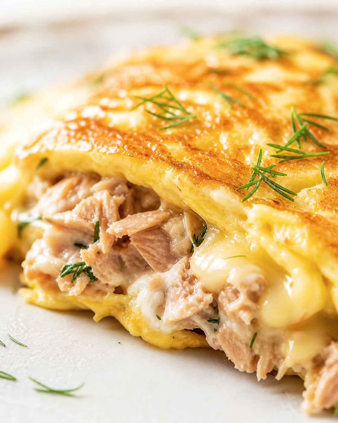 Close-up of golden puff-pastry chicken pot pie with creamy filling and dill garnish.