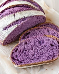 Sliced purple bread loaf with crusty exterior on parchment paper.