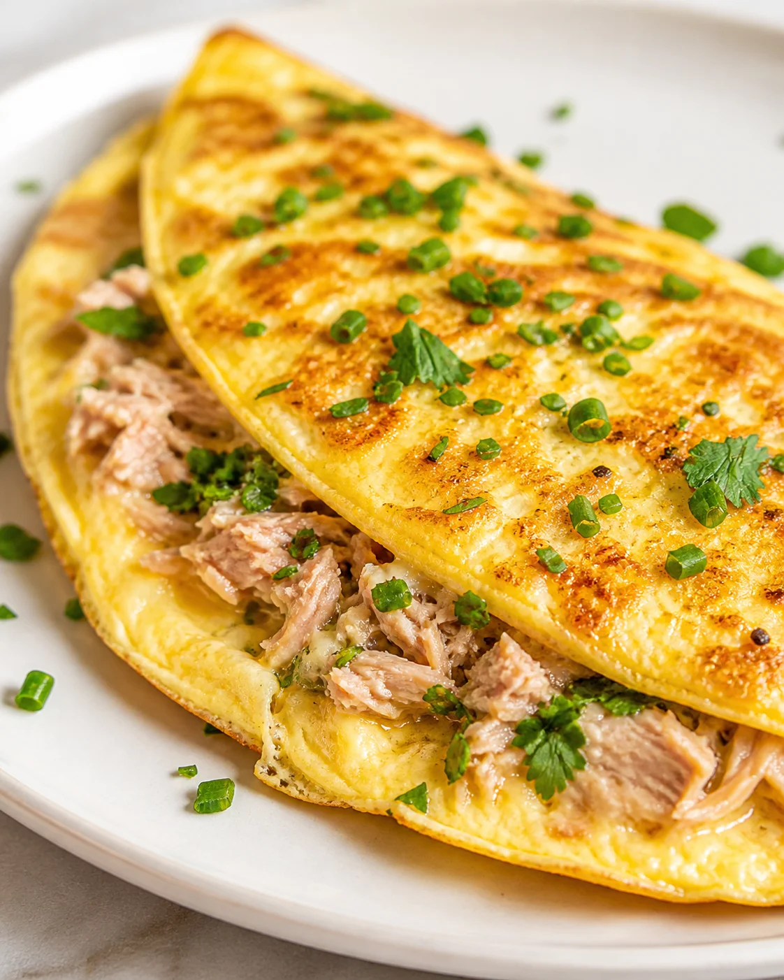 Golden-brown savory crepes filled with shredded meat and chopped herbs on a white plate.