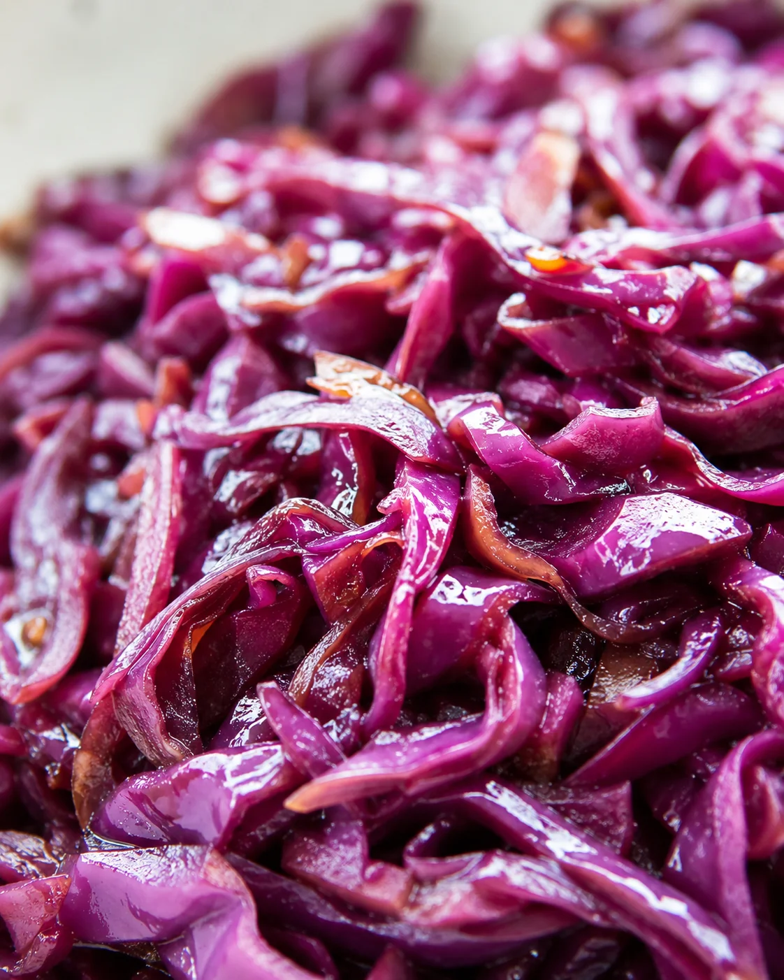 Close-up of glossy purple-red cabbage ribbons piled together, glistening with moisture