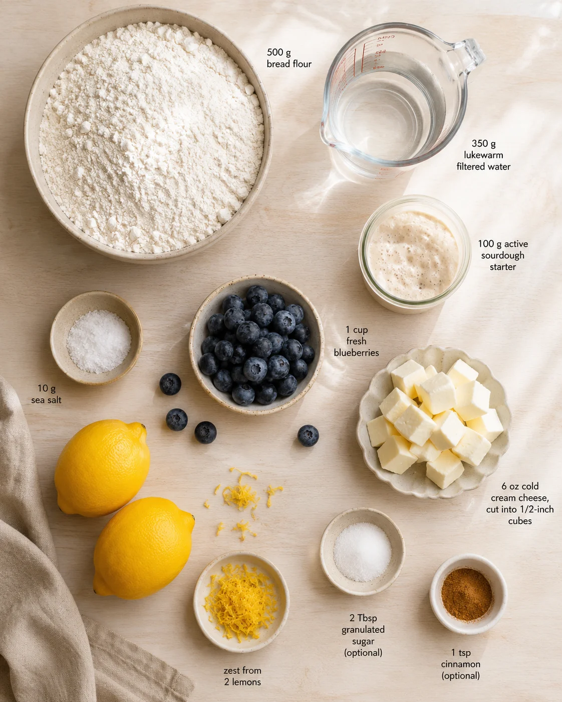 Top-down view of flour, water, starter, blueberries, and cheese cubes laid out for sourdough recipe.