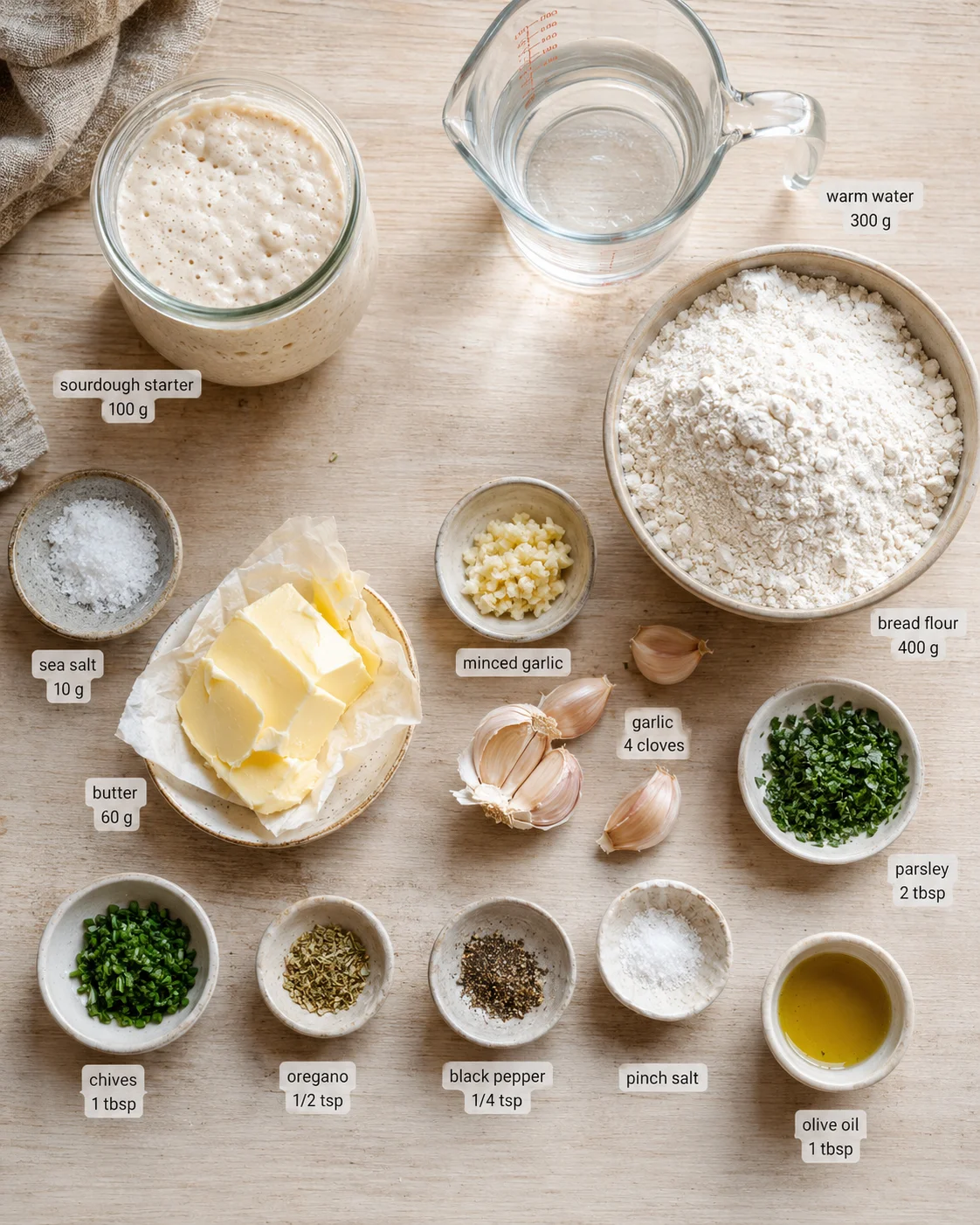 Overhead view of sourdough ingredients laid out on wood with labeled jars and bowls