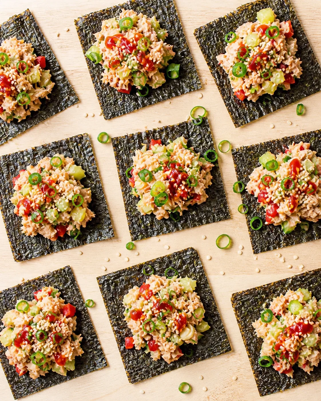 square seaweed sheets topped with tuna-avocado salad, cucumber, red pepper, sesame seeds, and green onion rings