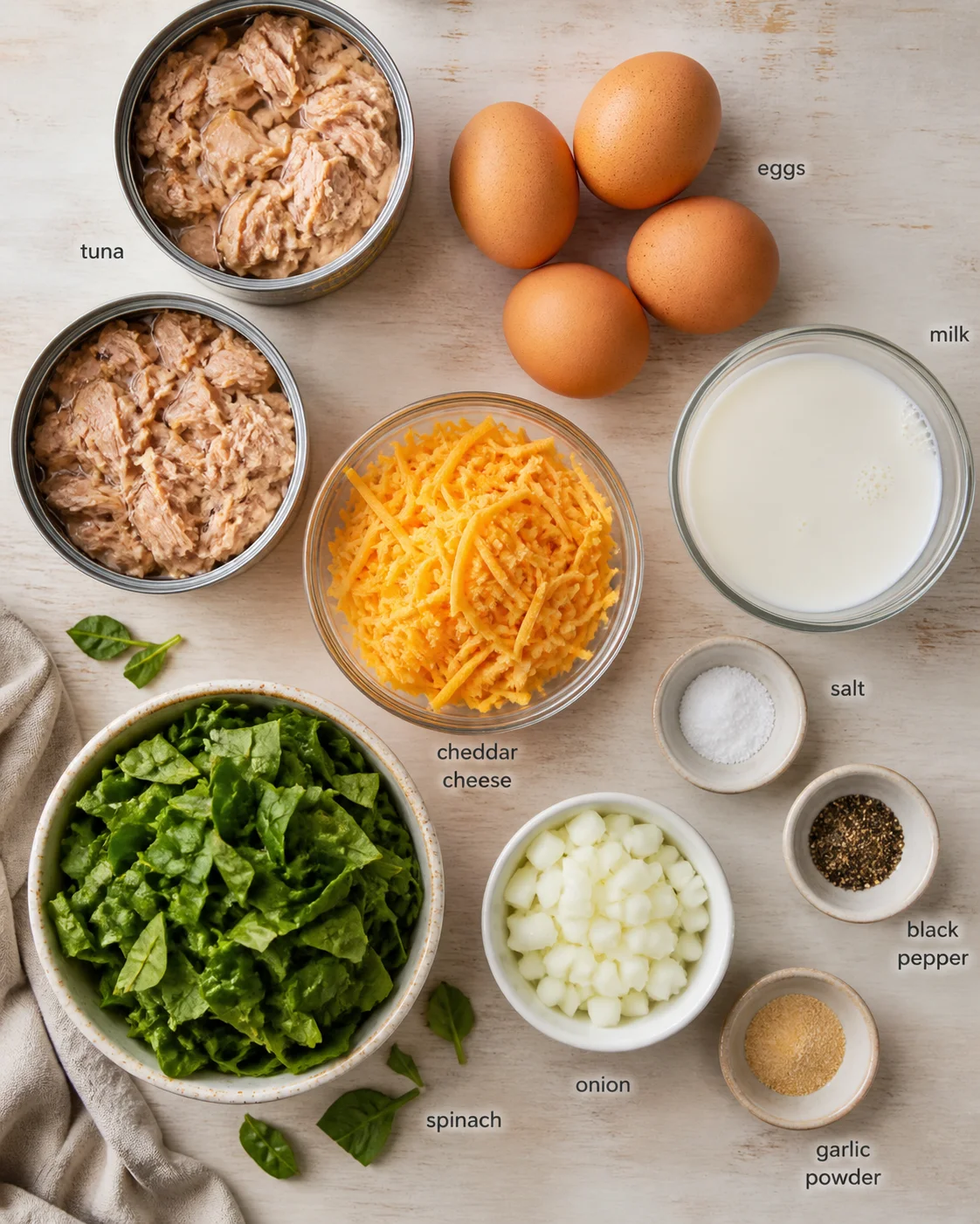 top-down view of labeled tuna, eggs, milk, cheddar, spinach, onion, and spices