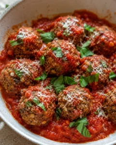 Plate of vegetarian eggplant meatballs topped with tomato sauce, basil, and cheese