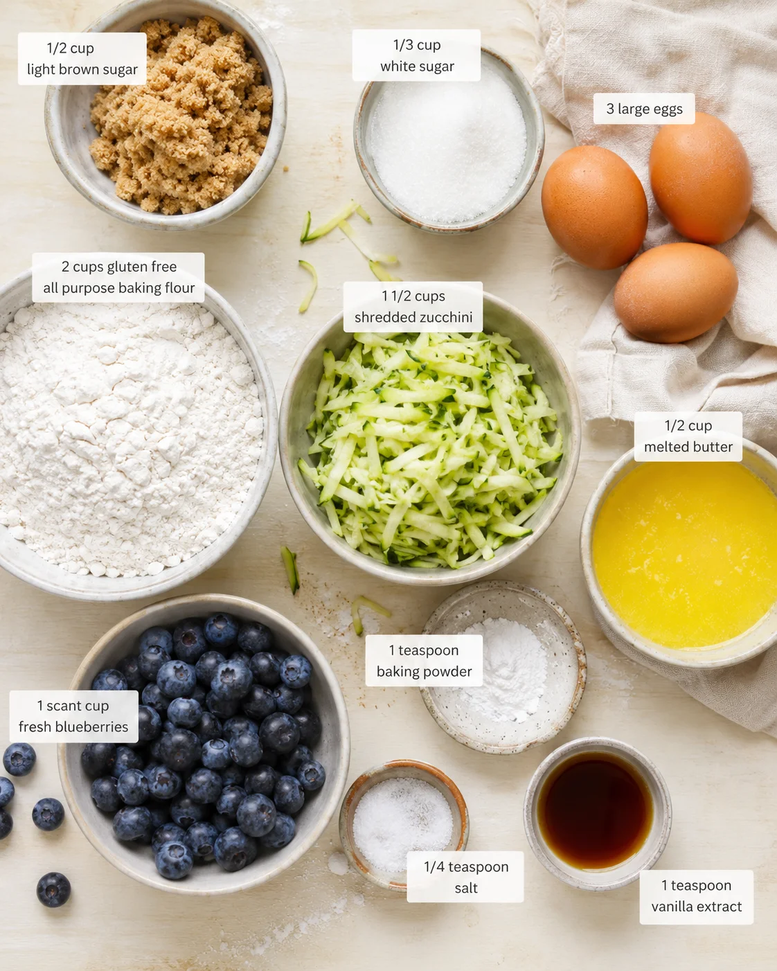 Overhead view of gluten-free baking ingredients arranged in bowls on a light wooden surface.