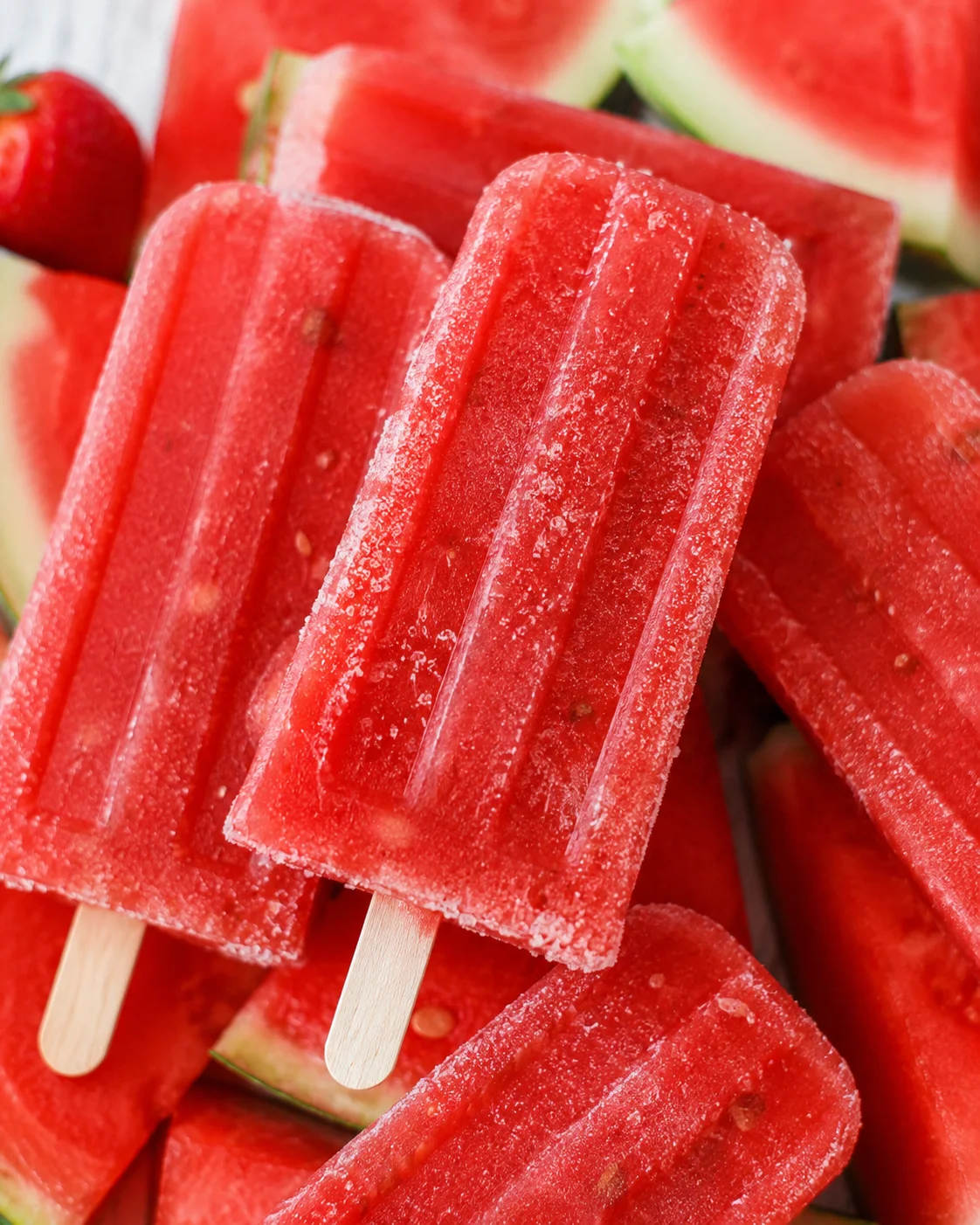 Close-up of vibrant homemade strawberry watermelon popsicles with wooden sticks