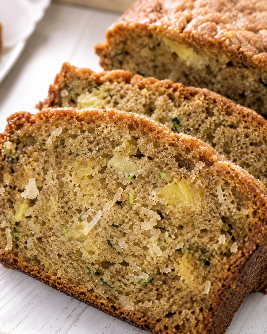 Close-up of moist zucchini bread filled with pineapple and coconut pieces, sliced.