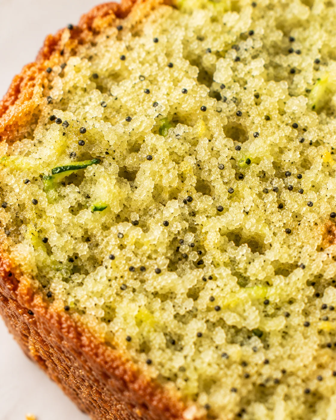 Freshly baked lemon zucchini bread topped with poppy seeds and a golden crust.
