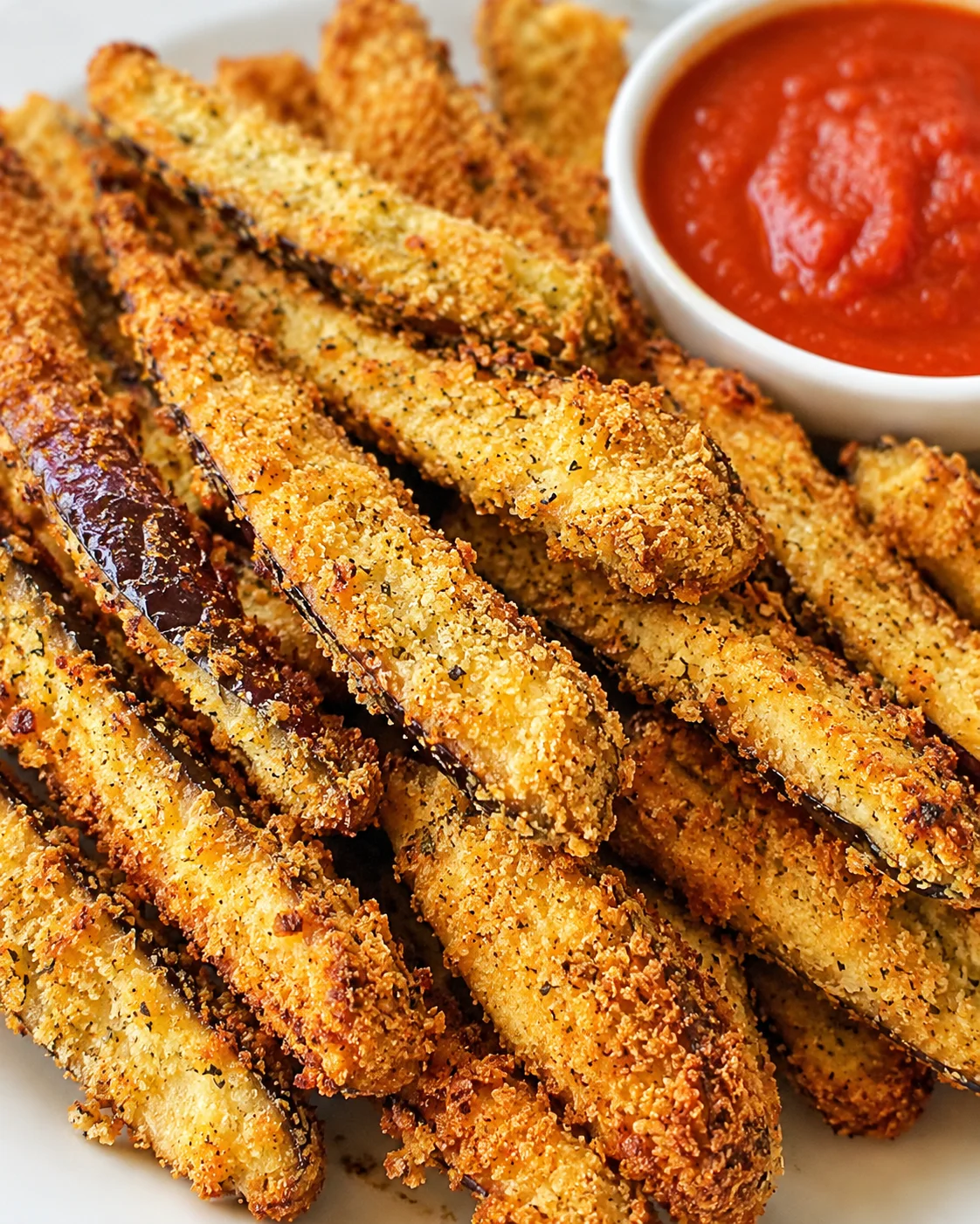 Golden crispy eggplant fries with a side of marinara sauce, baked in an air fryer.