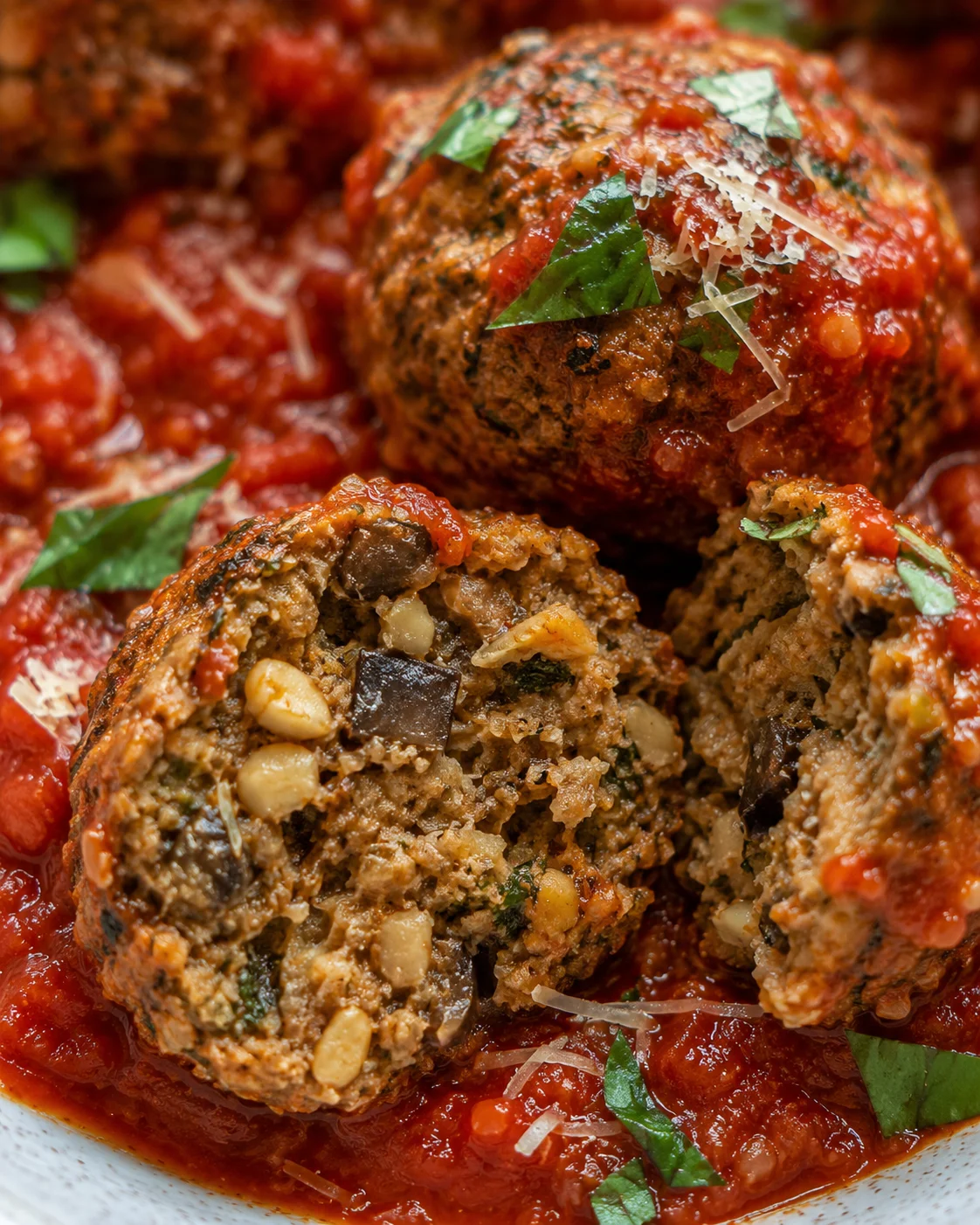Close-up of cooked vegetarian eggplant and mushroom meatballs served with tomato sauce.