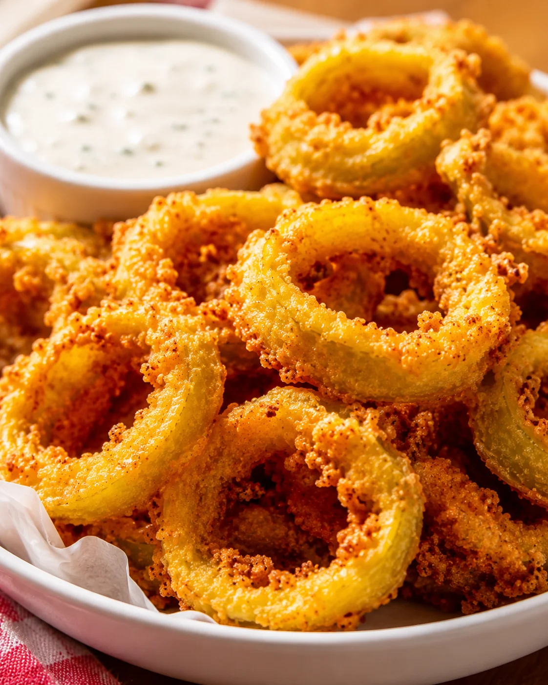 Golden crispy fried banana peppers served with dipping sauce on a plate.