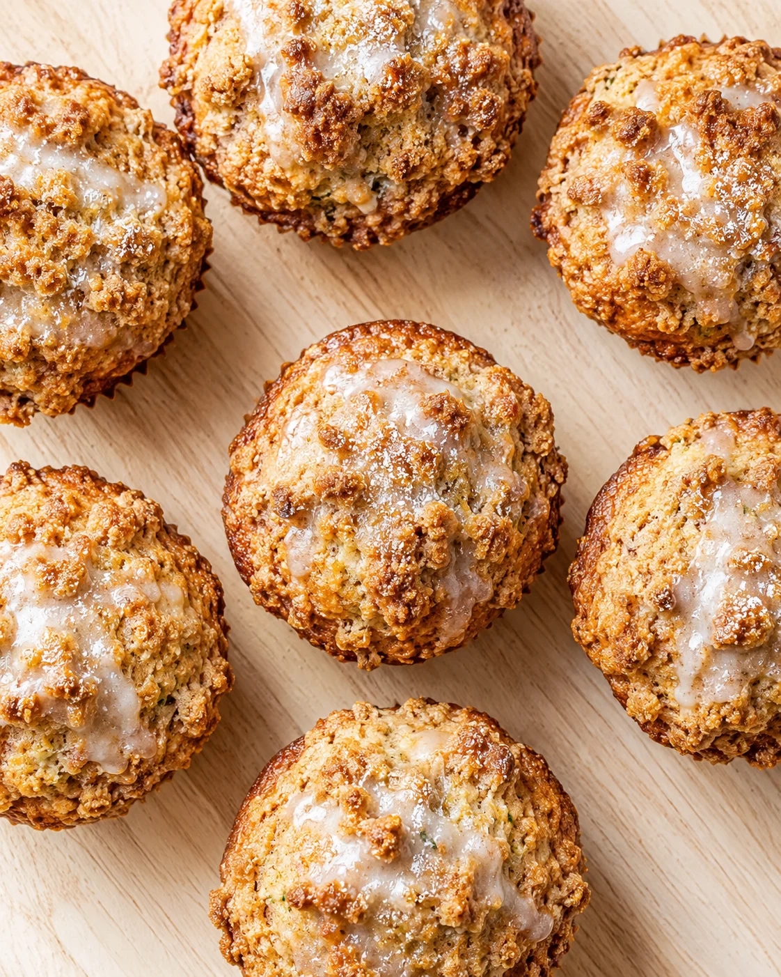 Close-up of glazed, crumbly streusel-topped donut holes on a wooden surface.