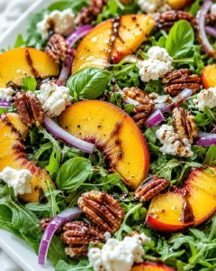 Colorful summer peach salad with greens, peaches, pecans, and balsamic glaze