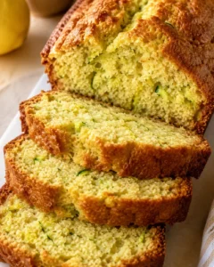 Moist and delicious lemon zucchini bread with a golden crust and green zucchini specks.