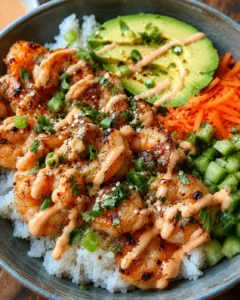 Colorful shrimp rice bowls topped with sliced avocado, carrots, cucumber, and spicy mayo