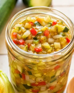Colorful jar of sweet and tangy zucchini relish with chopped vegetables inside.
