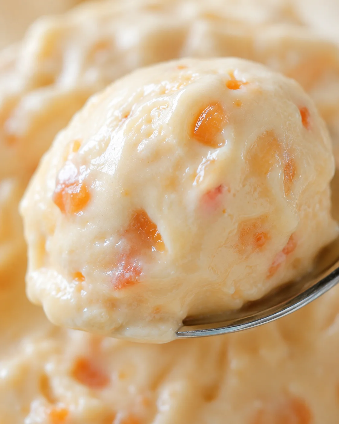 Close-up of creamy nectarine frozen yogurt with vibrant fruit pieces.
