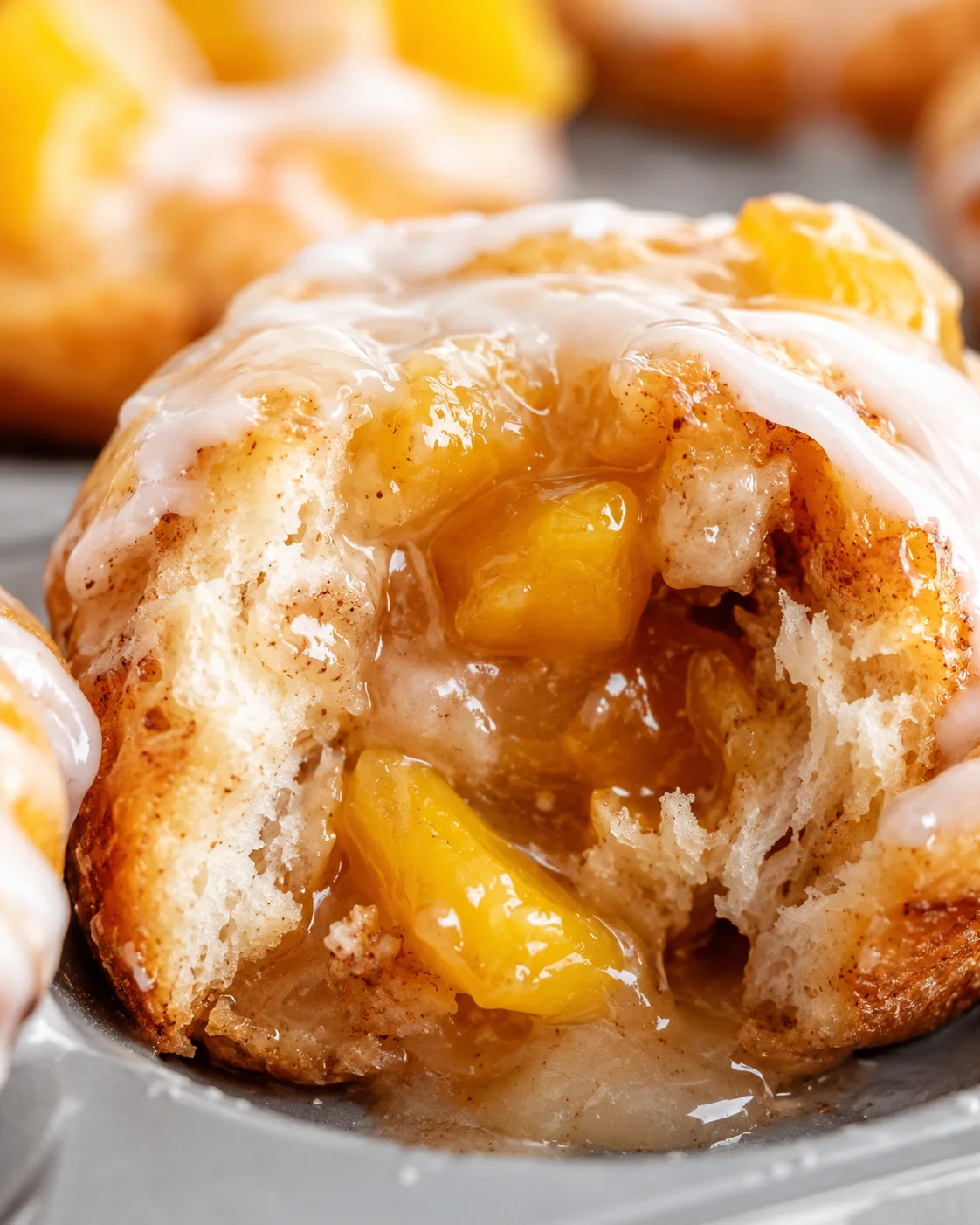 Close-up of a warm mini peach pie with gooey filling and icing drizzle.