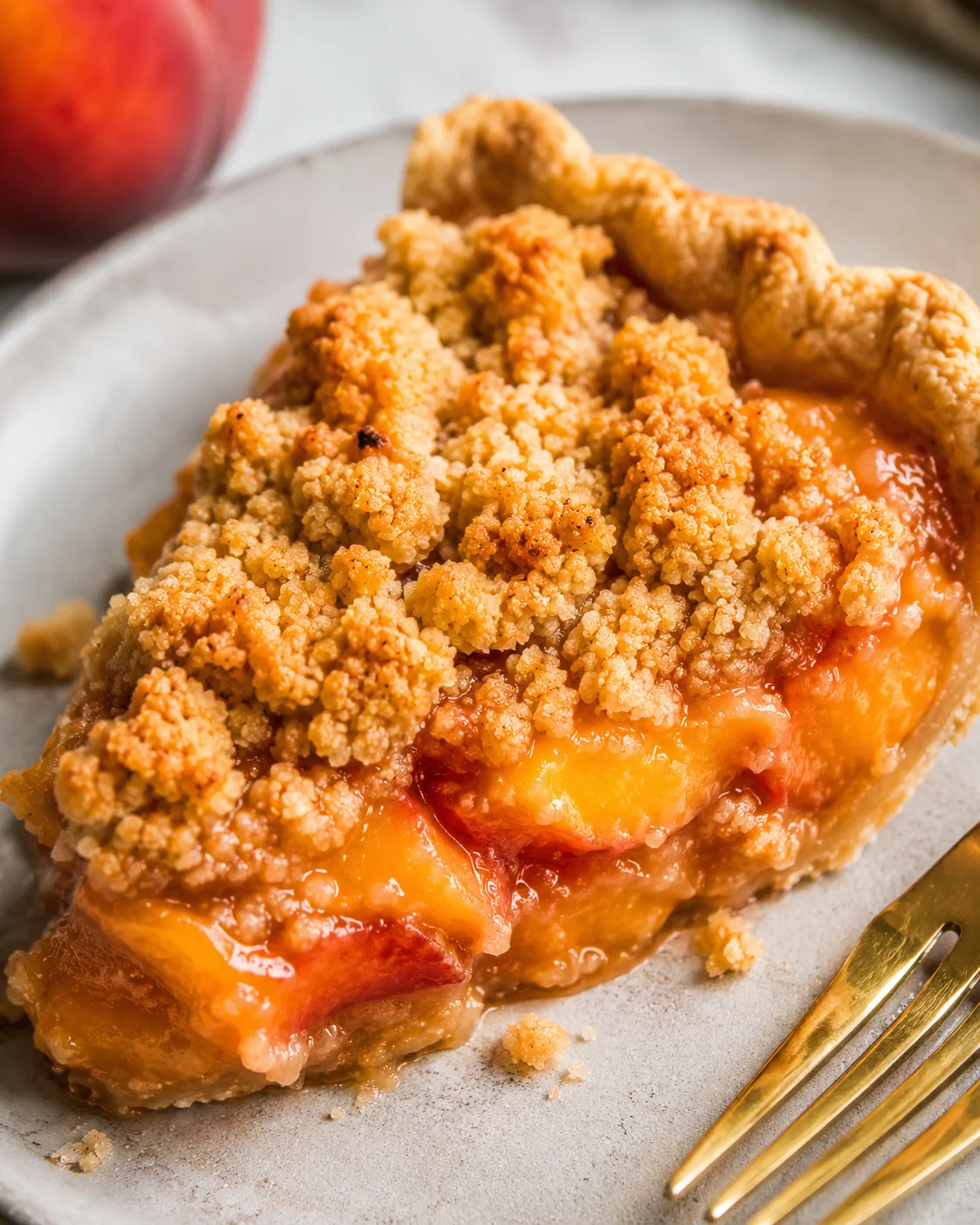 Close-up of a golden peach crumble pie with a buttery crumble topping