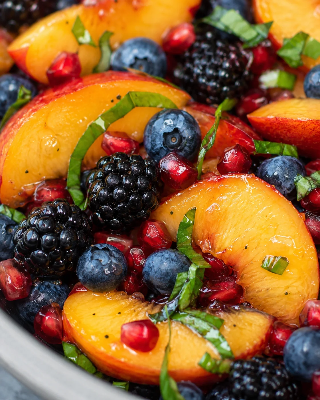 Honey Lime Basil Peach Fruit Salad Colorful peach and berry fruit salad with basil and pomegranate seeds