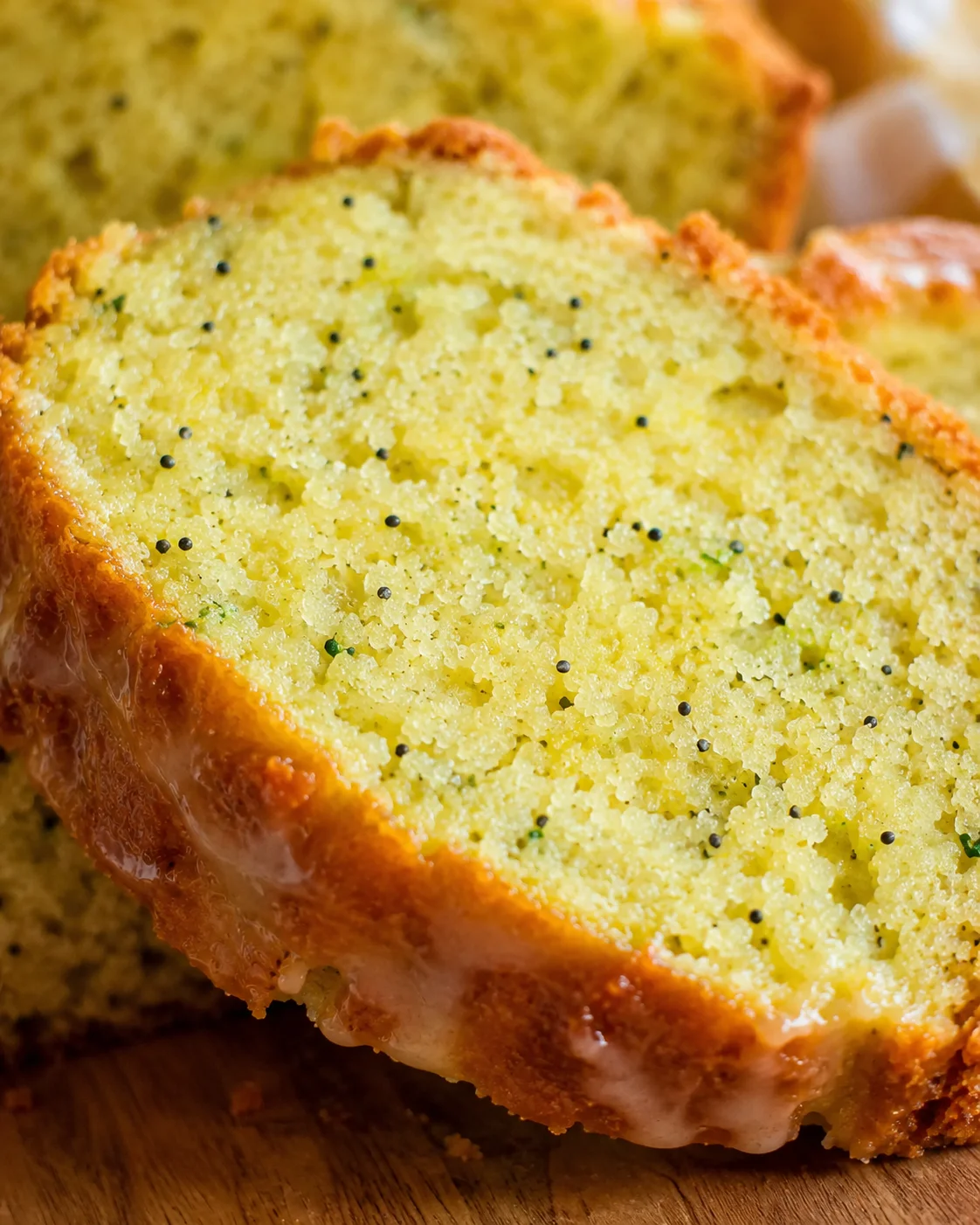 Close-up of moist lemon zucchini bread with poppy seeds and glaze.