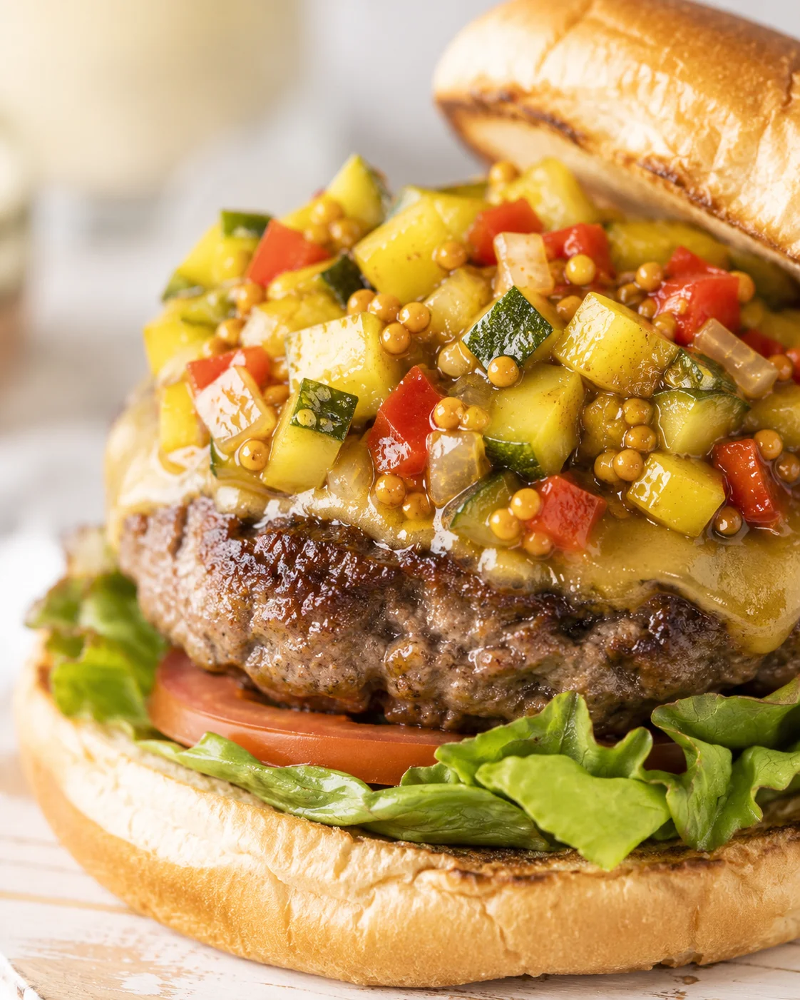 Close-up of a burger topped with colorful zucchini relish and fresh vegetables