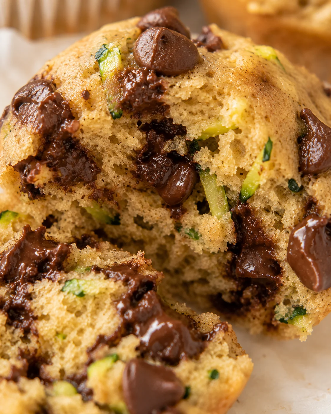 Close-up of moist zucchini chocolate chip muffins with gooey chocolate chunks.