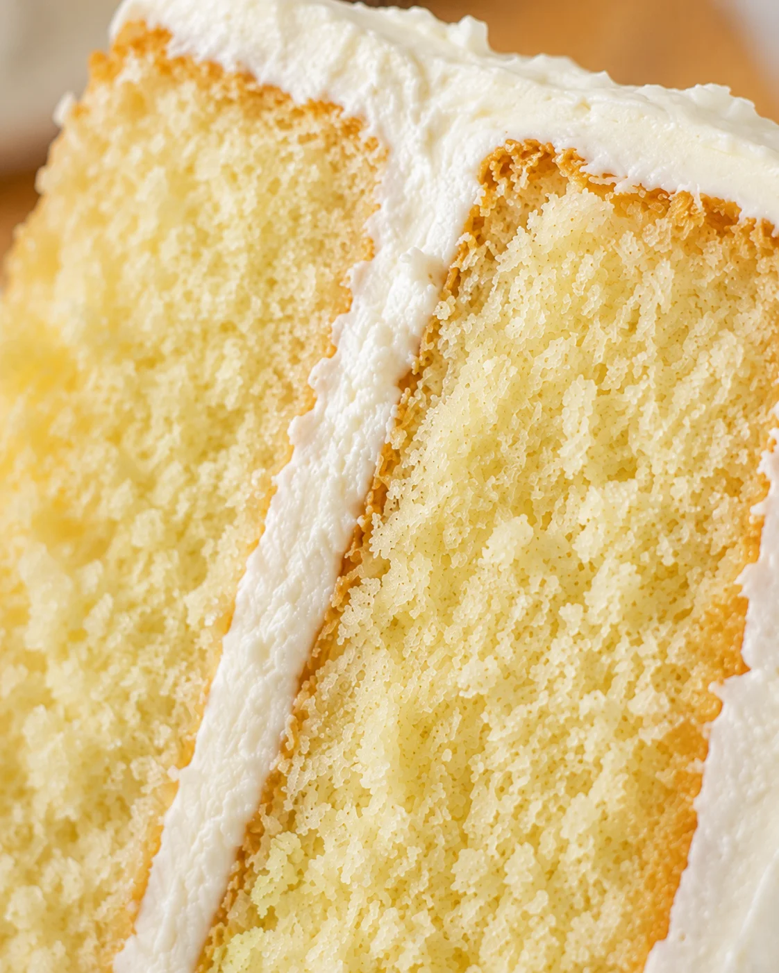 Close-up of a slice of fluffy vanilla cake with creamy frosting.
